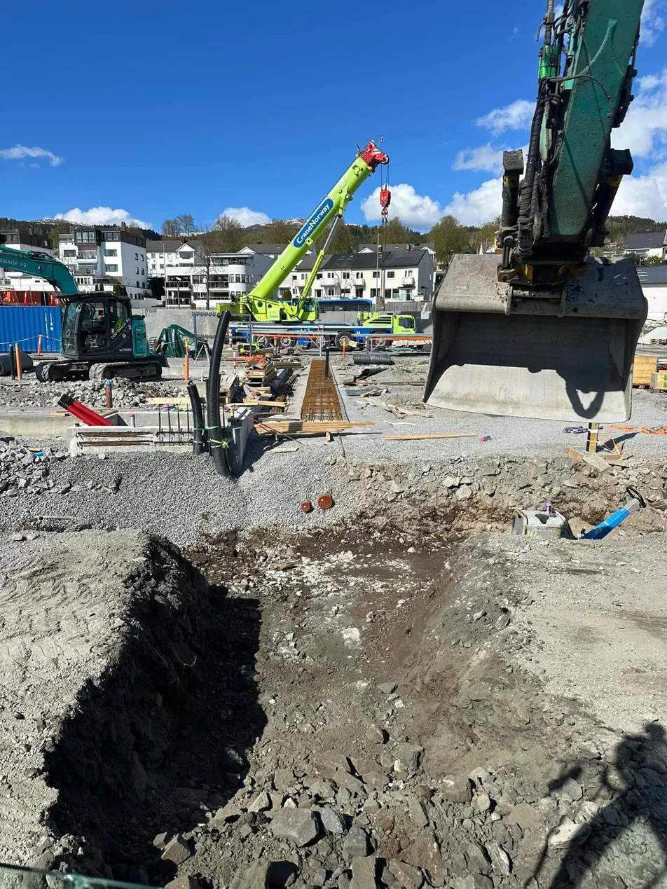 Byggeplass med grøn kran og gravemaskin